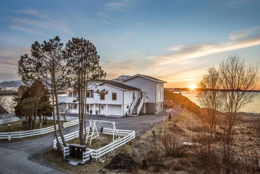 ein Haus auf einem Hügel mit Sonnenuntergang im Hintergrund in der Unterkunft Ytterland Apartments in Ålesund