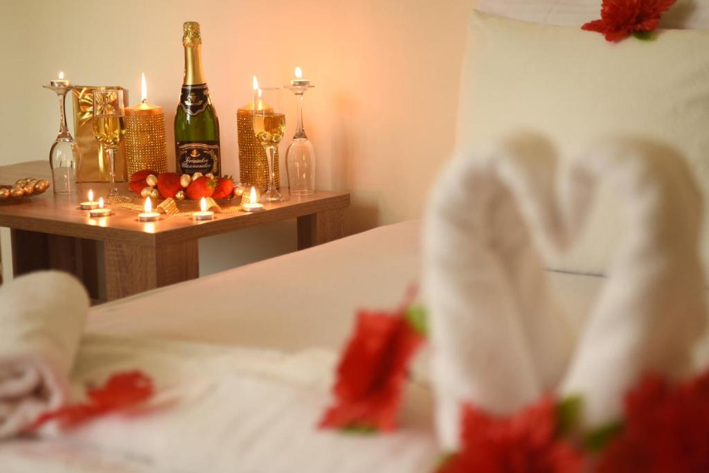 Una cama con velas y una mesa con botellas de champán. en Apartmani Boss, en Vrnjačka Banja