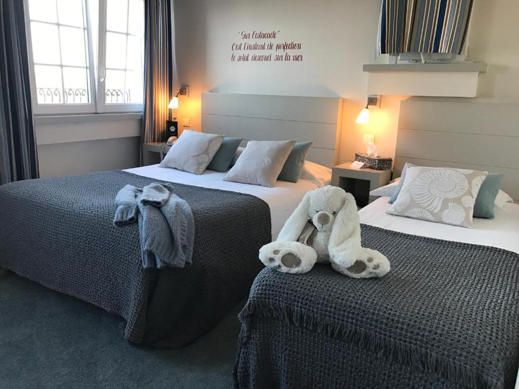 una habitación de hotel con dos camas con animales de peluche. en Hotel du Centre - Chez Janie, en Roscoff