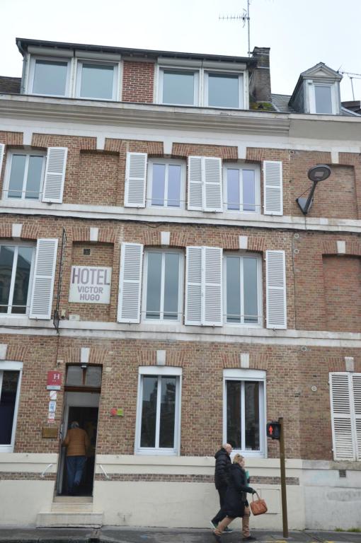 twee mensen die voor een bakstenen gebouw lopen bij Hotel Victor Hugo in Amiens