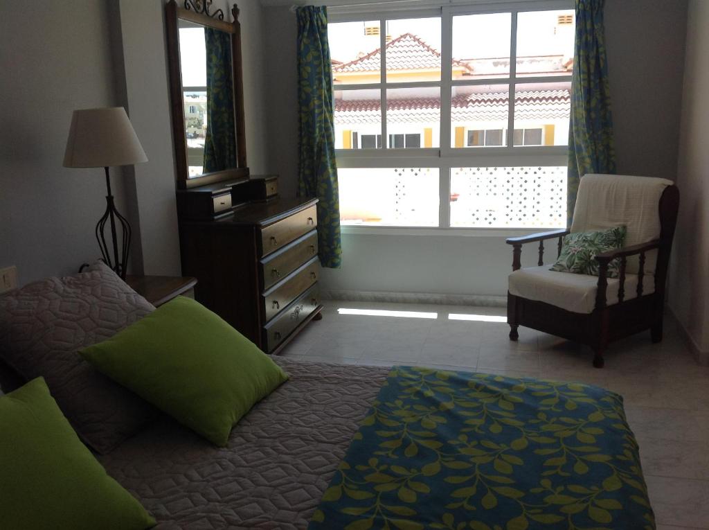 カレタ・デ・フステにあるAventura en Caleta de Fusteのベッドルーム1室(ベッド1台、椅子、窓付)
