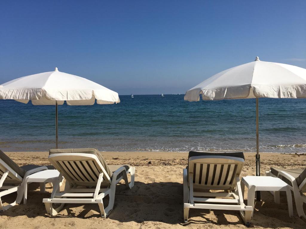 La Garonnette-PlageにあるJardins du Port Les Issambres - Meublé de Tourisme - Front de mer - Climの浜辺の椅子・傘