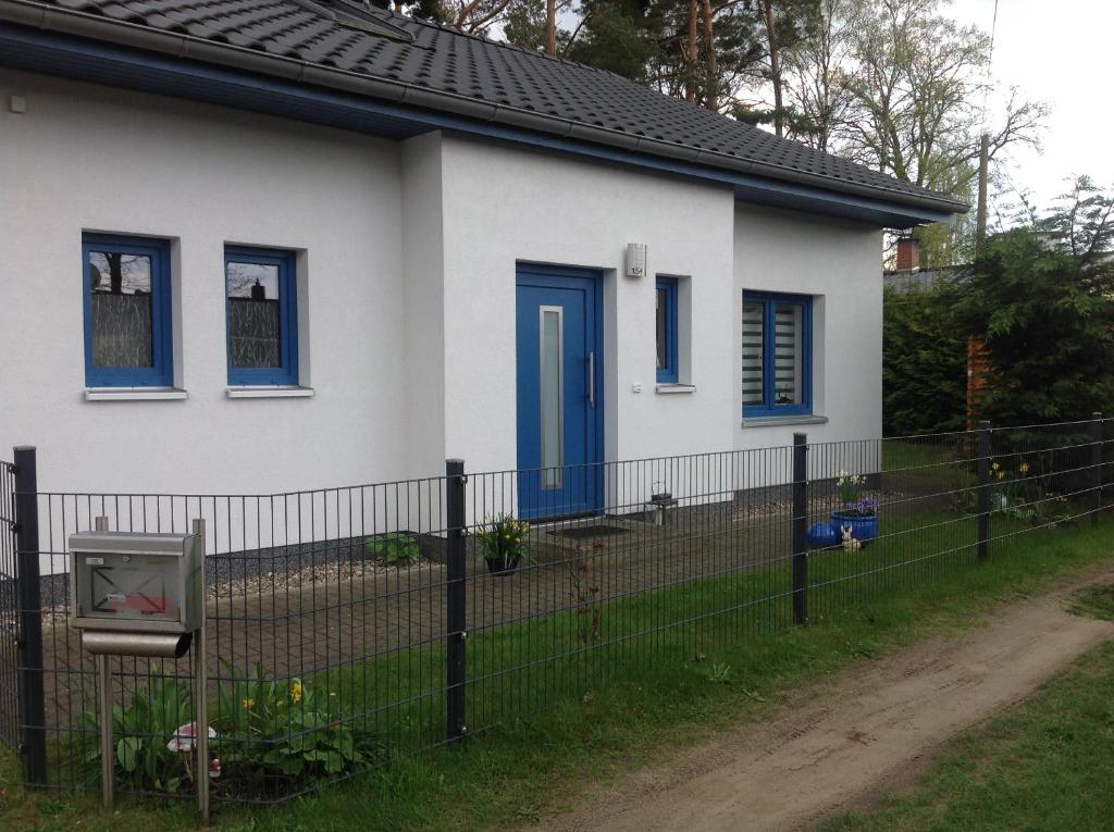 ein weißes Haus mit blauen Fenstern und einem Zaun in der Unterkunft Klünnersnest Graal Müritz in Graal-Müritz
