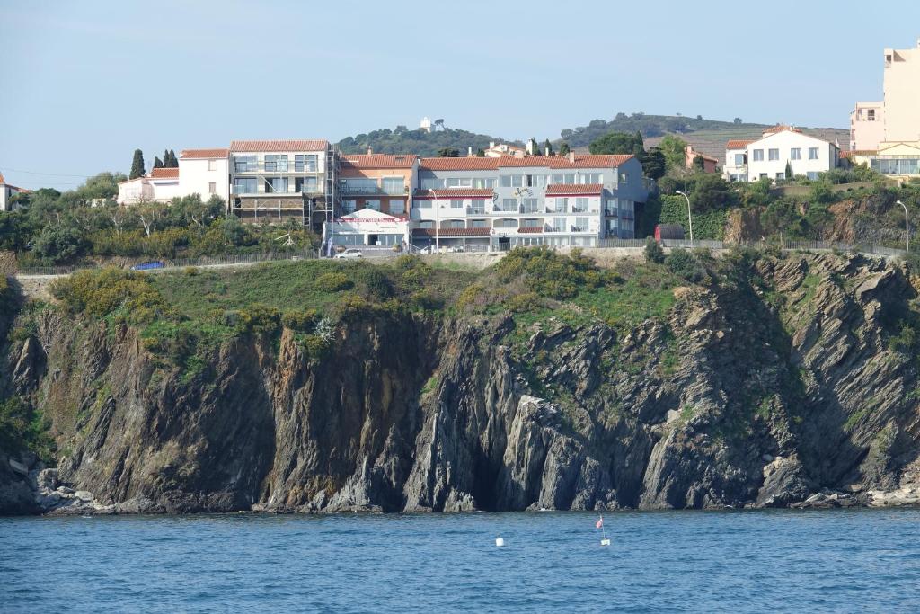 un groupe de maisons sur une falaise à côté de l'eau dans l'établissement Logis Hotel Solhotel, à Banyuls-sur-Mer