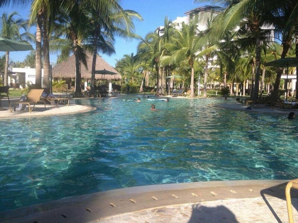 a pool with palm trees and people in the water at Departamento en La Isla Acapulco Torre H in Acapulco
