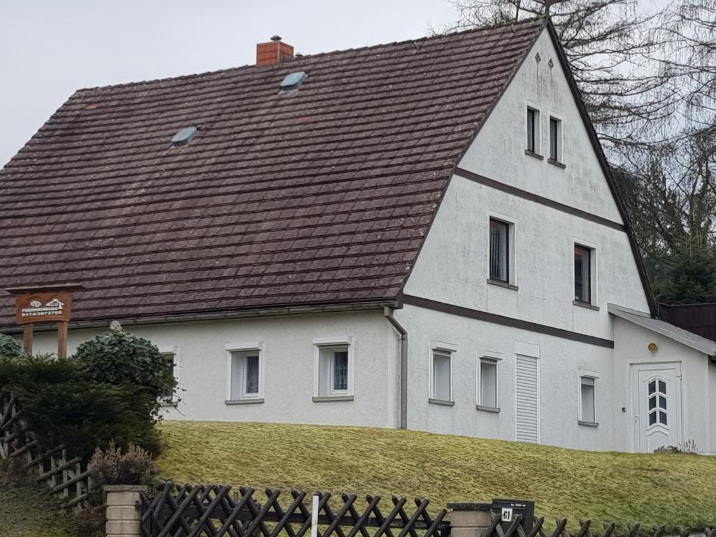 une grande maison blanche avec un toit marron dans l'établissement Ferienwohnung Schiller, à Jonsdorf