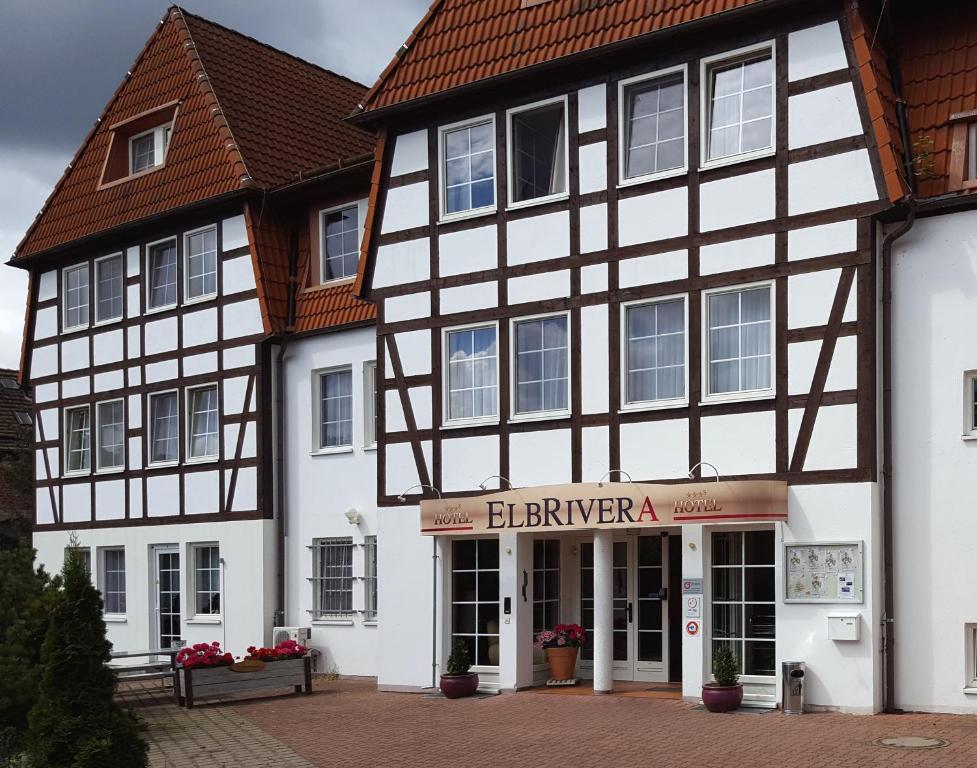 ein weißes und schwarzes Gebäude mit einem Laden in der Unterkunft Hotel ELBRIVERA Alt Prester in Magdeburg