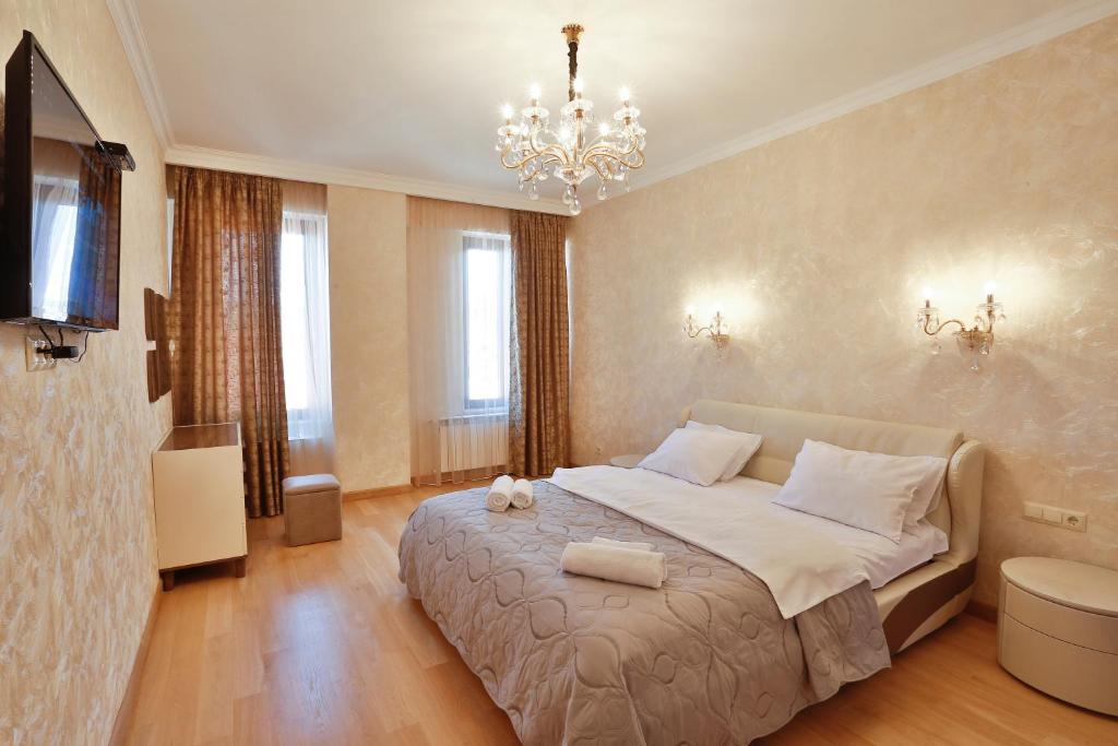 a bedroom with a large bed and a chandelier at Serviced Apartment on Rustaveli Avenue in Tbilisi City