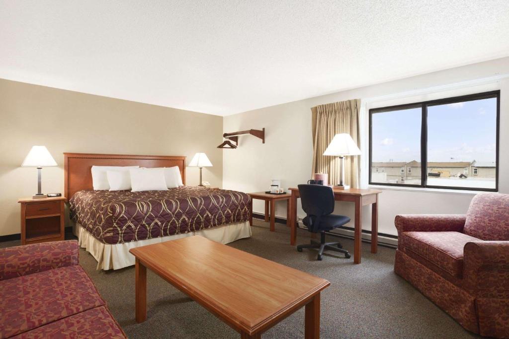 a hotel room with a bed and a desk and a couch at Super 8 by Wyndham Williston ND in Williston