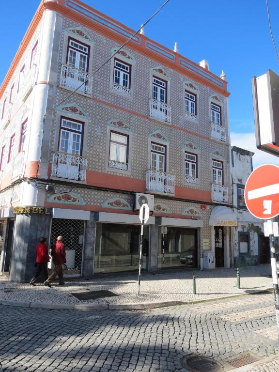 a building on a street with people walking past it at Alojamento Cesarini in Montijo