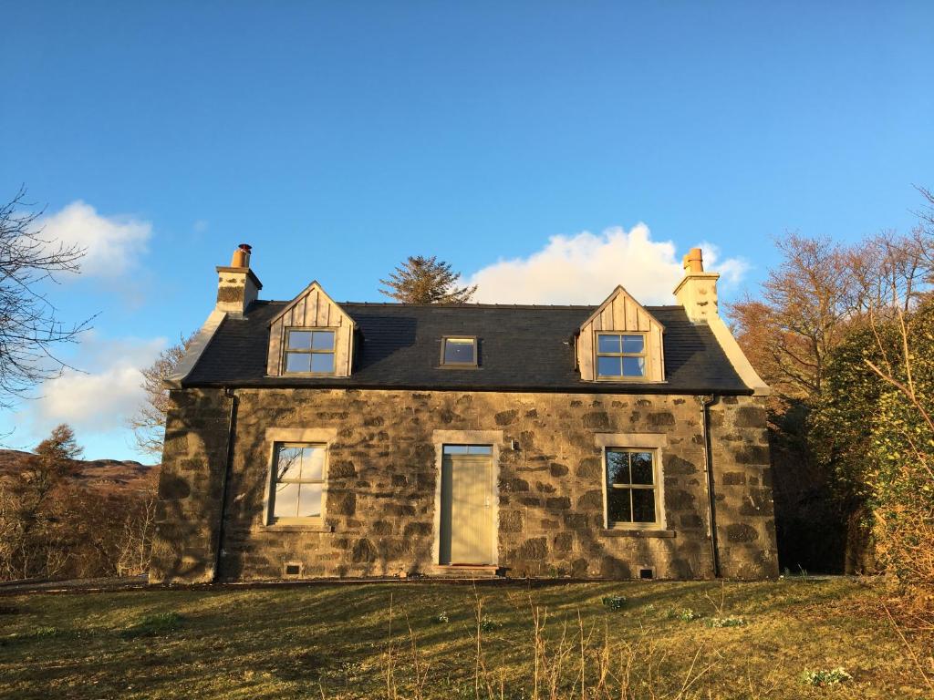 an old stone house on top of a field at Dunvegan Castle Keepers Cottage in Dunvegan