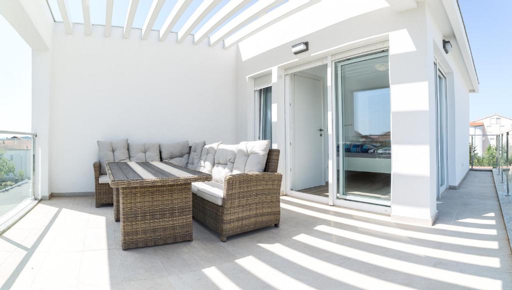 a patio with wicker chairs and a table on a balcony at Kuca Buzov - Holiday House in Croatia in Srima