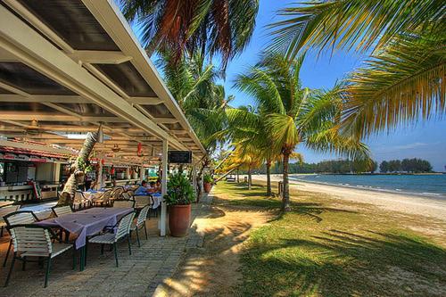 un tavolo e sedie su una spiaggia con palme di Mieqa@TheRegencyTanjungTuan (seafront unit) a Port Dickson