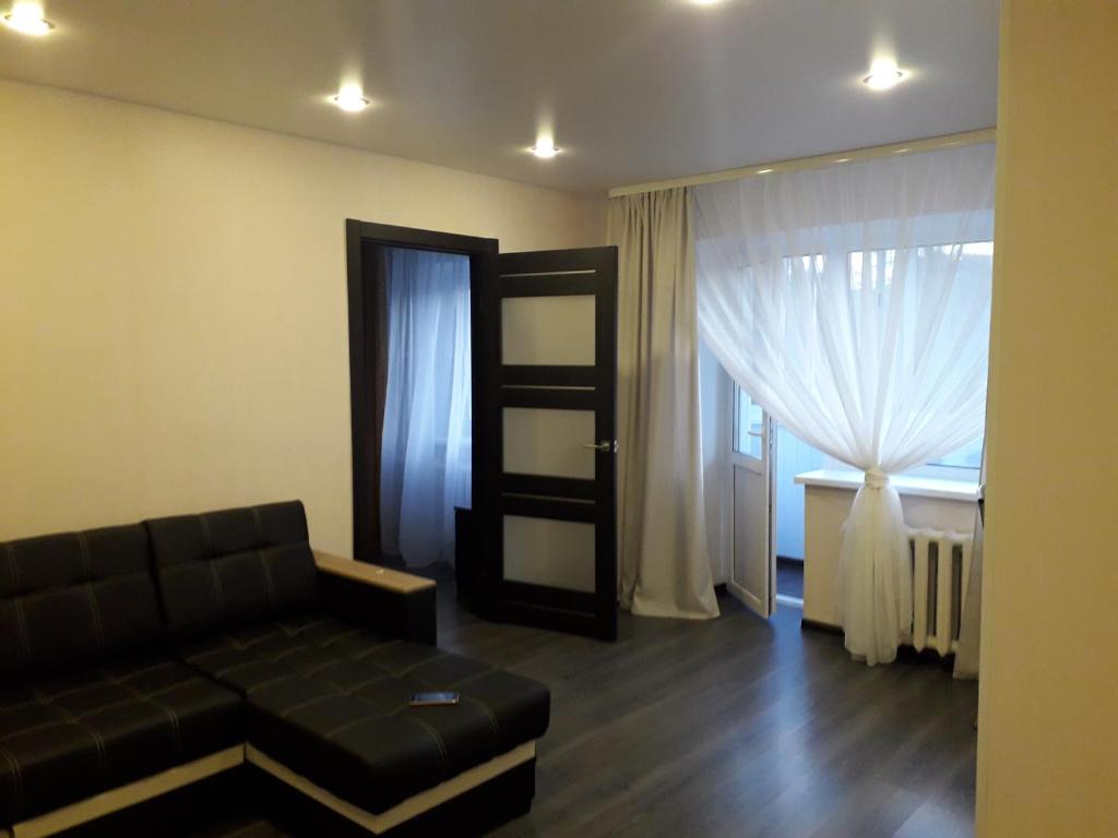 a living room with a black couch and a window at Apartment on Meretskova-Volosova in Velikiy Novgorod