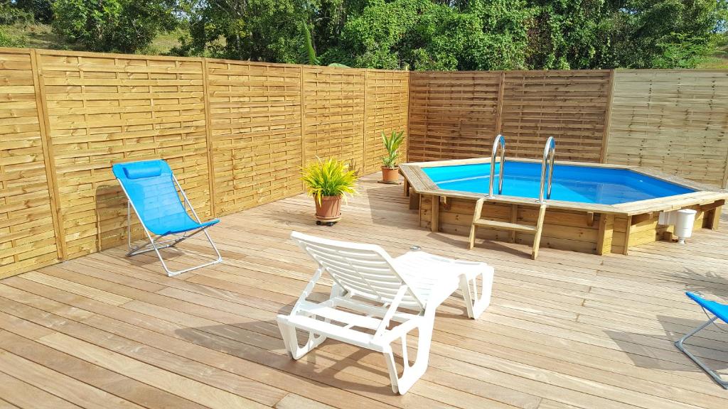 une terrasse avec des chaises, une piscine et une clôture en bois dans l'établissement Cocon des Alizés, à Le Moule