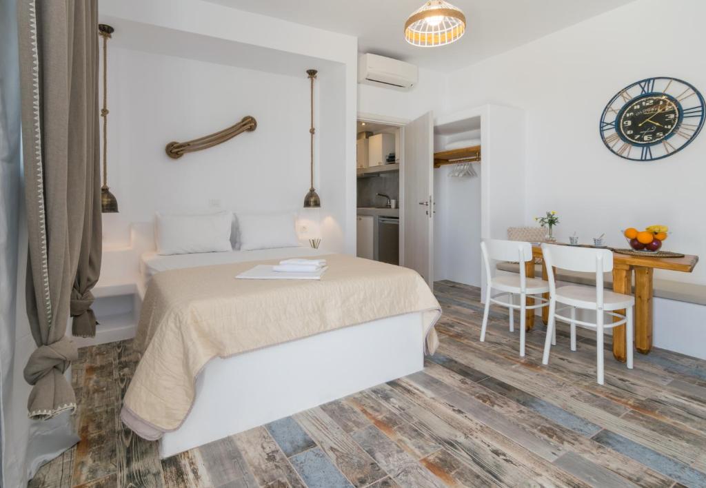een witte slaapkamer met een bed en een tafel en stoelen bij Giannoulis Hotel in Adamas
