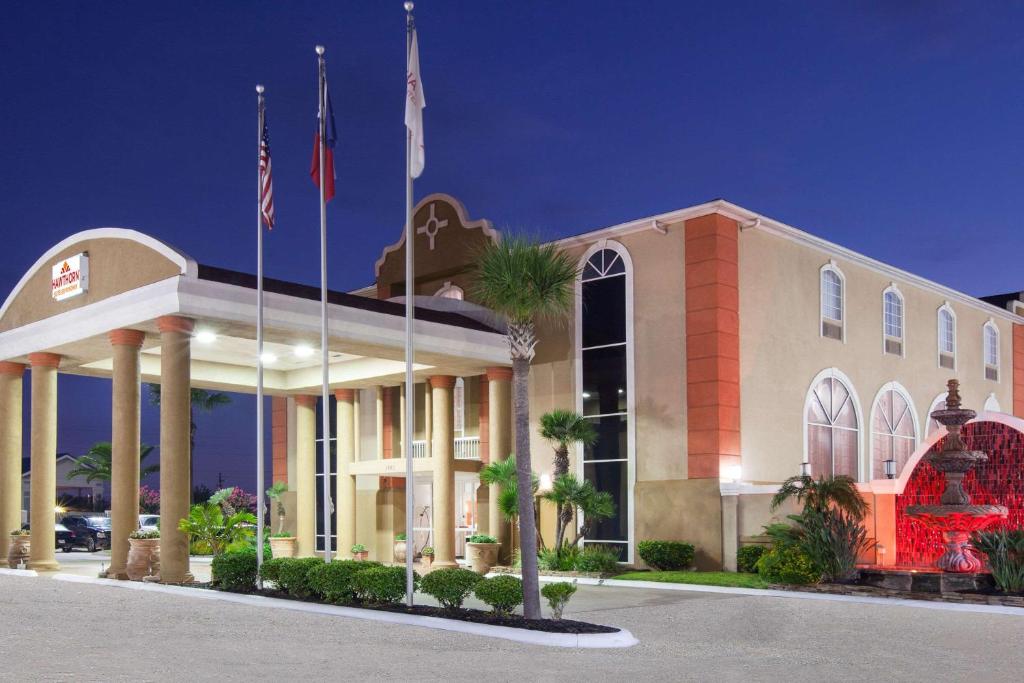 Un hotel con banderas frente a un edificio. en Hawthorn Extended Stay by Wyndham Corpus Christi, en Corpus Christi