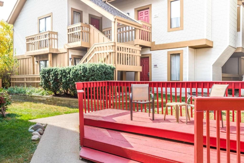 Hawthorn Suites Dayton North في دايتون: سطح احمر مع طاولة وكراسي امام المنزل