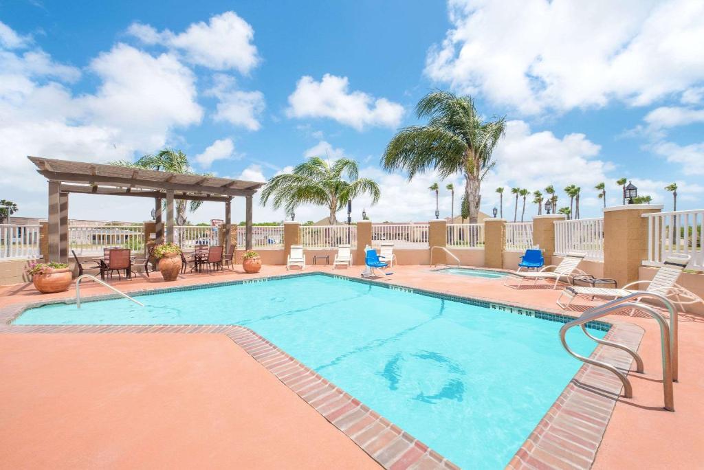 a swimming pool with chairs and a gazebo at Microtel Inn & Suites by Wyndham Corpus Christi/Aransas Pass in Aransas Pass