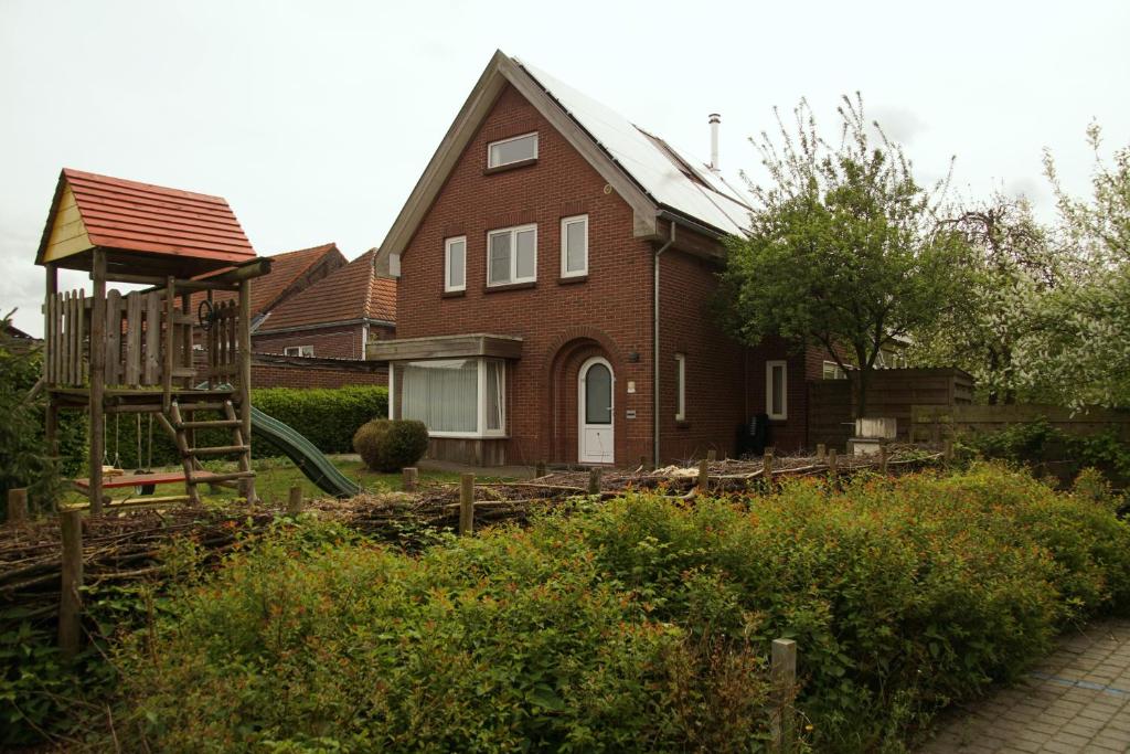 una casa con un parque infantil delante de ella en Holiday Home Op 't Busselen, en Opoeteren