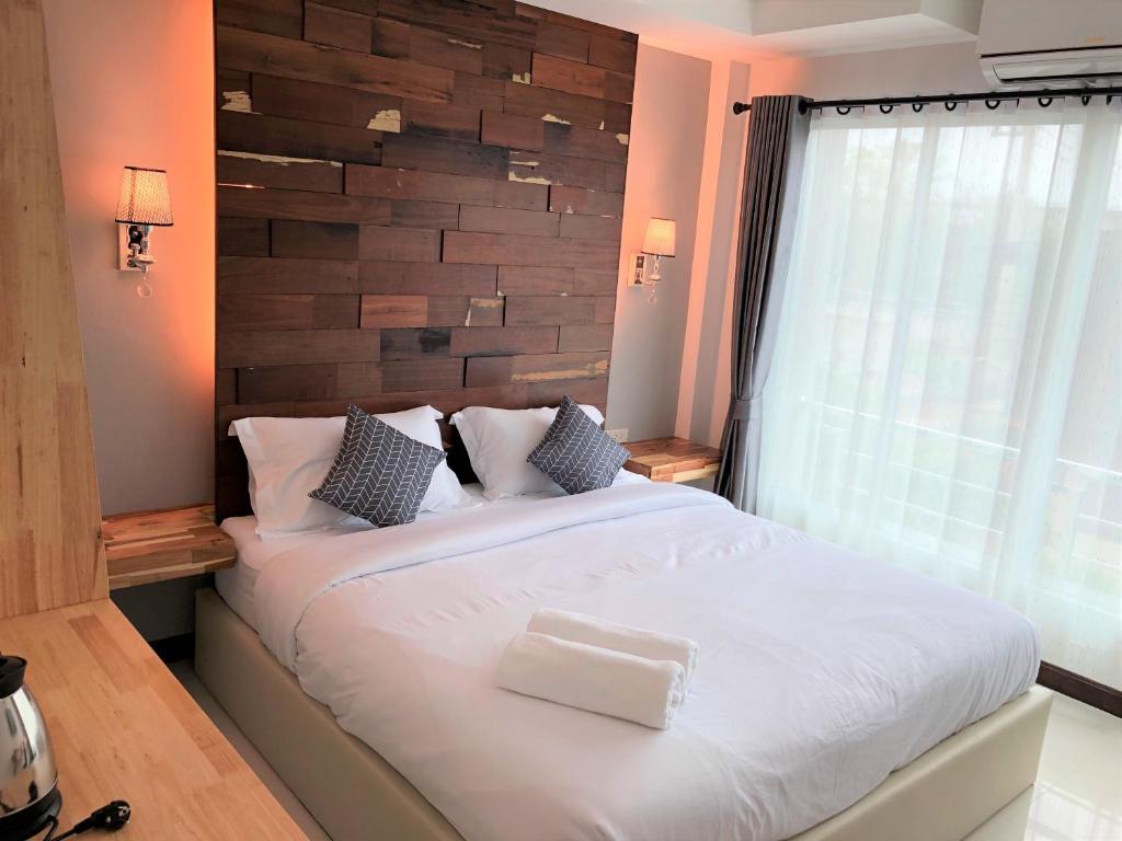 a bedroom with a large white bed with a wooden wall at Nan Panwa Hotel in Nan