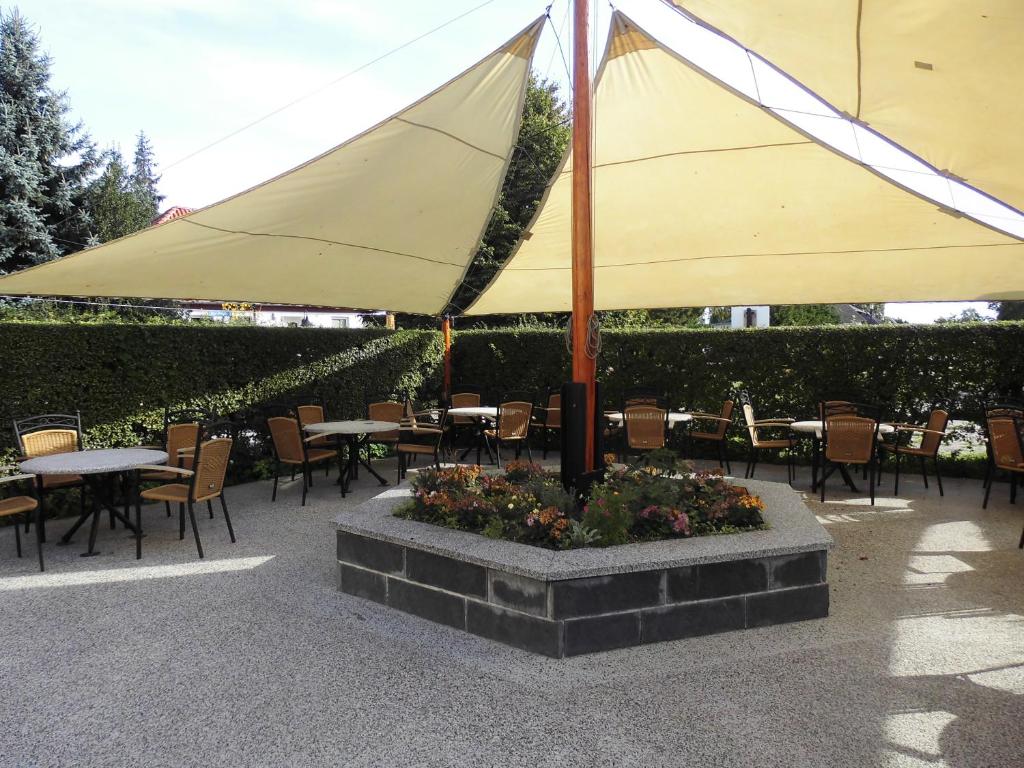 a large yellow umbrella in a patio with tables and chairs at Eiscafe&Pension Schumann in Bresewitz