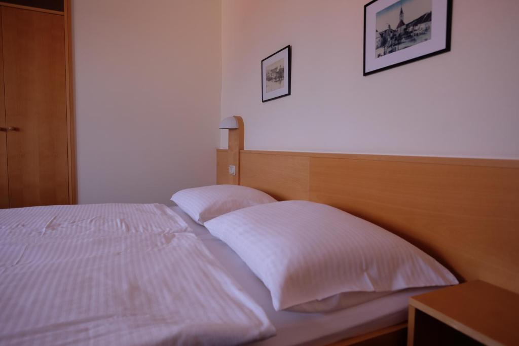 - un lit avec des draps et des oreillers blancs dans une chambre dans l'établissement Mokahotel, à Drosendorf Stadt