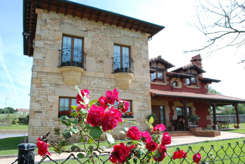 una casa con rosas rojas delante de una valla en Posada La Fabula en Santillana del Mar