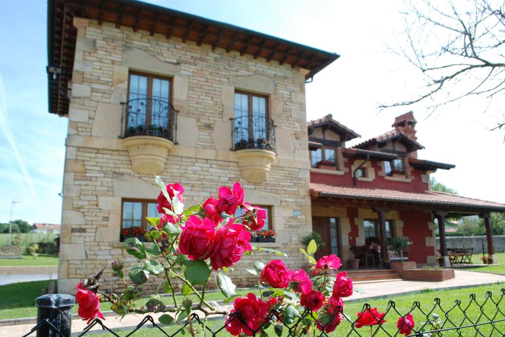 a house with red roses in front of a fence at Posada La Fabula in Santillana del Mar
