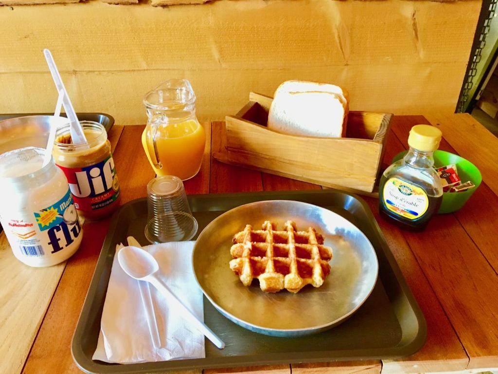 a table with a plate of waffles and a tray of food at Les Tipis du Bonheur de Vivre in Brûlon