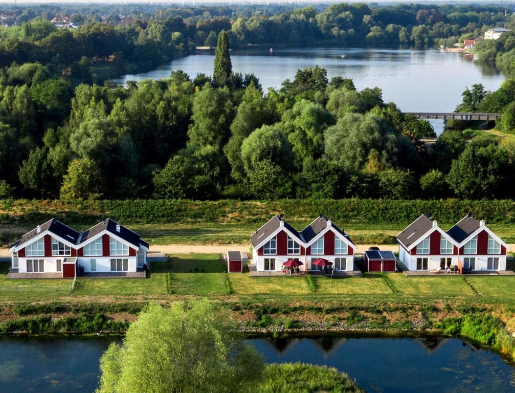 een rij huizen op een heuvel naast een rivier bij Ferienhaus Nordhorn - Haus Am See in Nordhorn