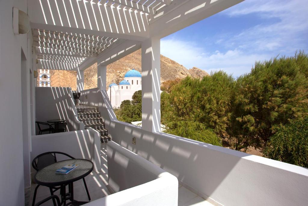 a white patio with a table and chairs on a balcony at SUN -RISE in Perissa