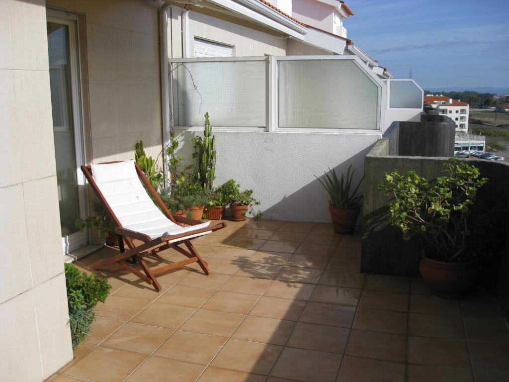 uma cadeira branca sentada numa varanda com plantas em Casa do Terraço em Aveiro