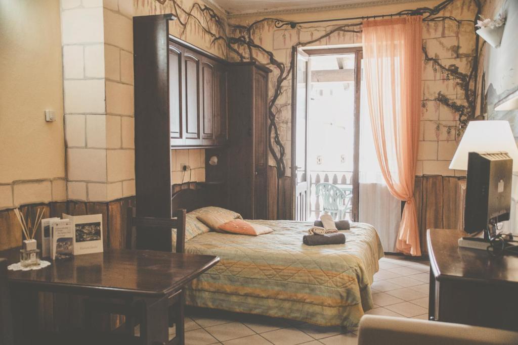 Schlafzimmer mit einem Bett, einem Tisch und einem Fenster in der Unterkunft Ristorante Residence Giardini in Piode