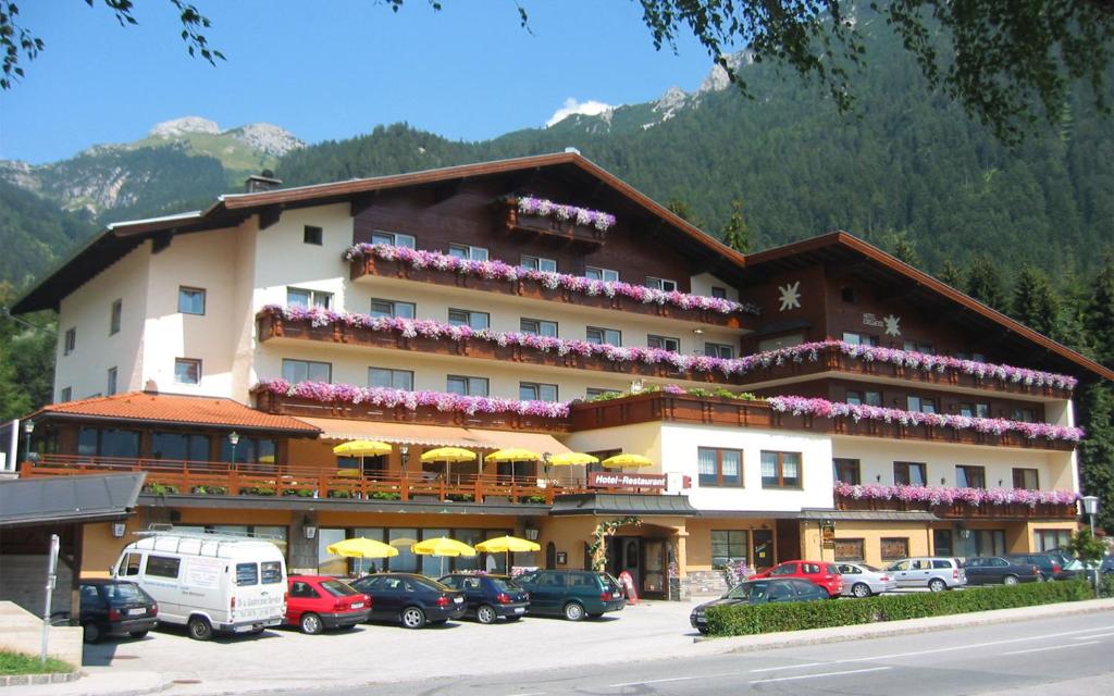 een groot hotel met auto's geparkeerd op een parkeerplaats bij Alpenhotel Edelweiss in Maurach