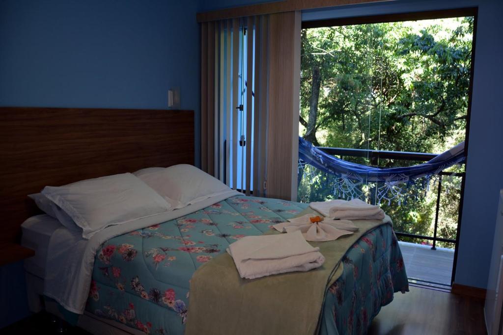 a bedroom with a bed with towels and a window at Pousada Zero Grau in Nova Friburgo