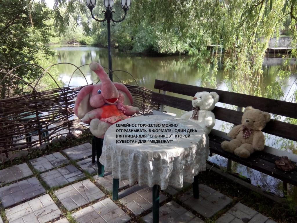 dos ositos de peluche y un pájaro rosa sentado en un banco del parque en Guest House Dacha, en Kiev