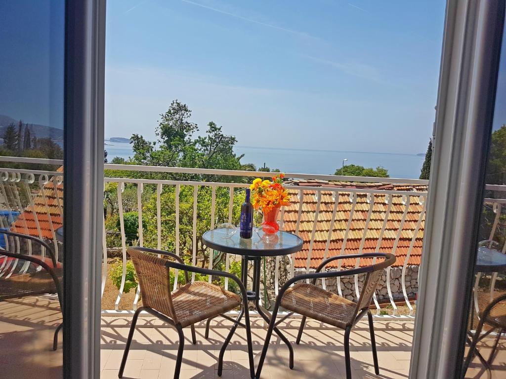 een tafel met stoelen en een vaas met bloemen op een balkon bij Apartments Dalmatia Blue in Mlini