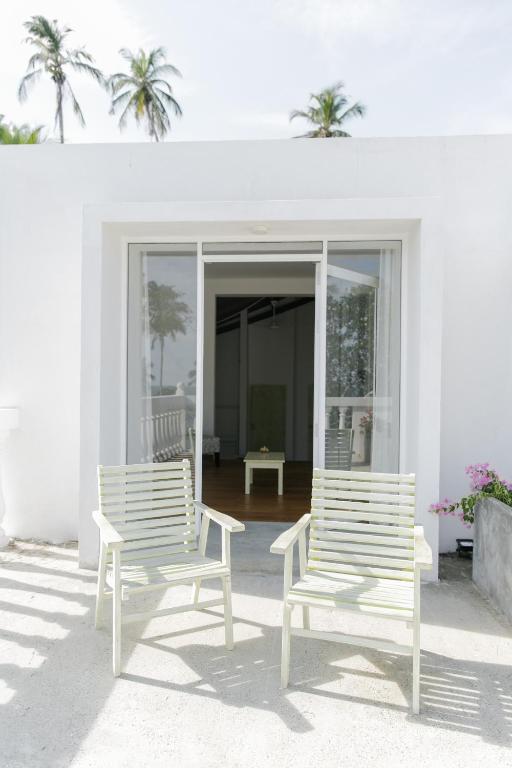 two white chairs sitting on a patio in front of a house at Nuga Eden Tangalle in Tangalle