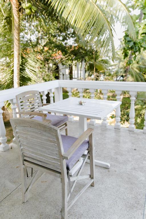 a white table and a bench with a table and chairs at Nuga Eden Tangalle in Tangalle