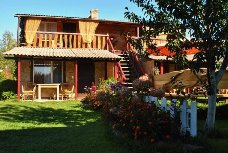 une maison avec une terrasse couverte et une cour fleurie dans l'établissement Садиба "ОРНАМЕНТ", à Szack
