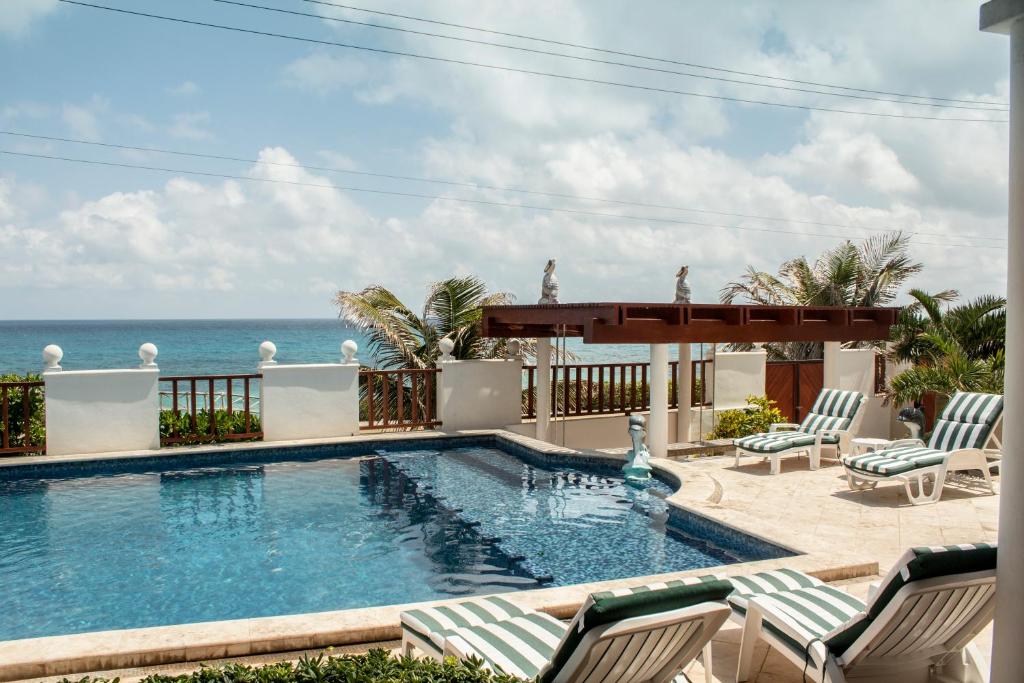 una piscina con sillas y el océano en el fondo en Villa Isla Dorada, en Isla Mujeres