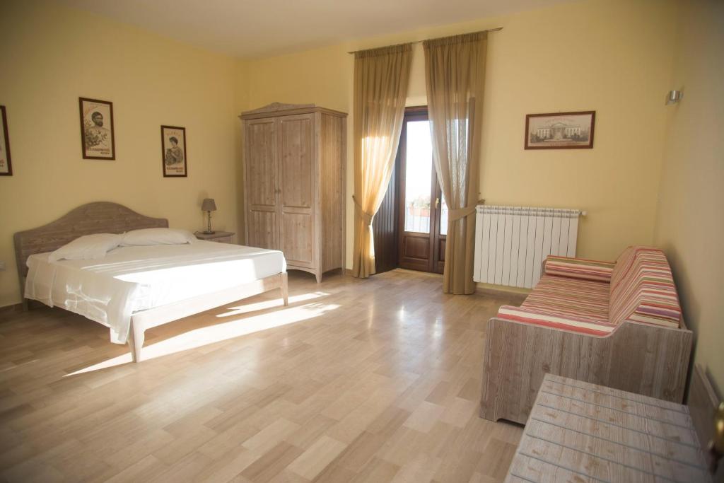 1 dormitorio con 1 cama y suelo de madera en L'Antico Monastero, en SantʼAgata di Puglia