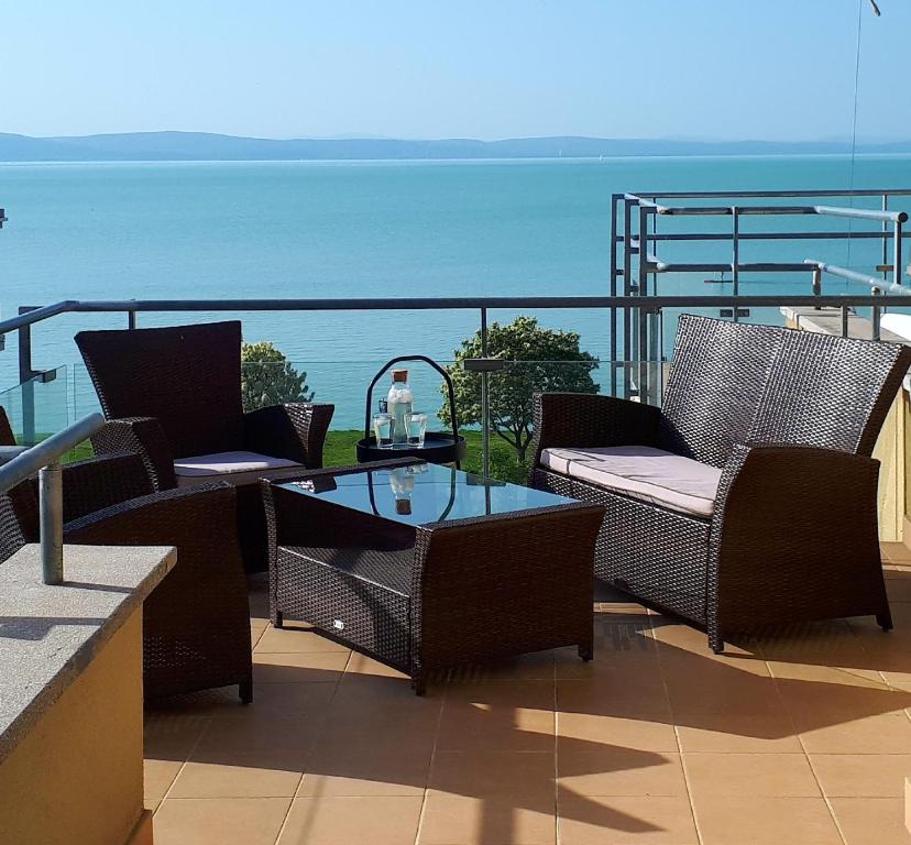 patio z krzesłami i stołem oraz oceanem w obiekcie Balaton-Golden Beach Apartman Siófok-Aranypart-Apartman w Siófoku