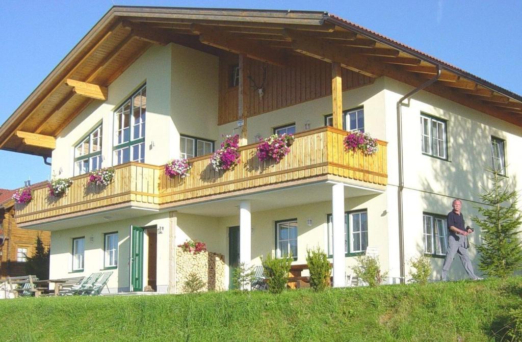 a man standing in front of a house with a balcony at Haus Rigl in Schladming