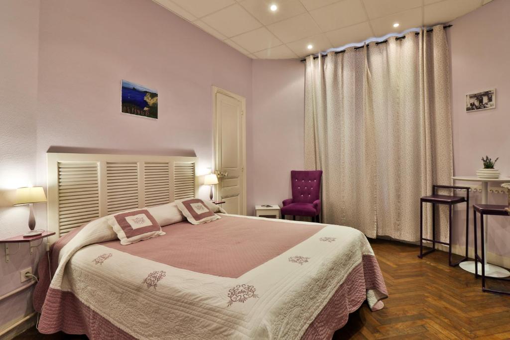ニースにあるホテル ヴィクトル ユーゴー ニースのベッドルーム(大型ベッド1台、紫色の椅子付)