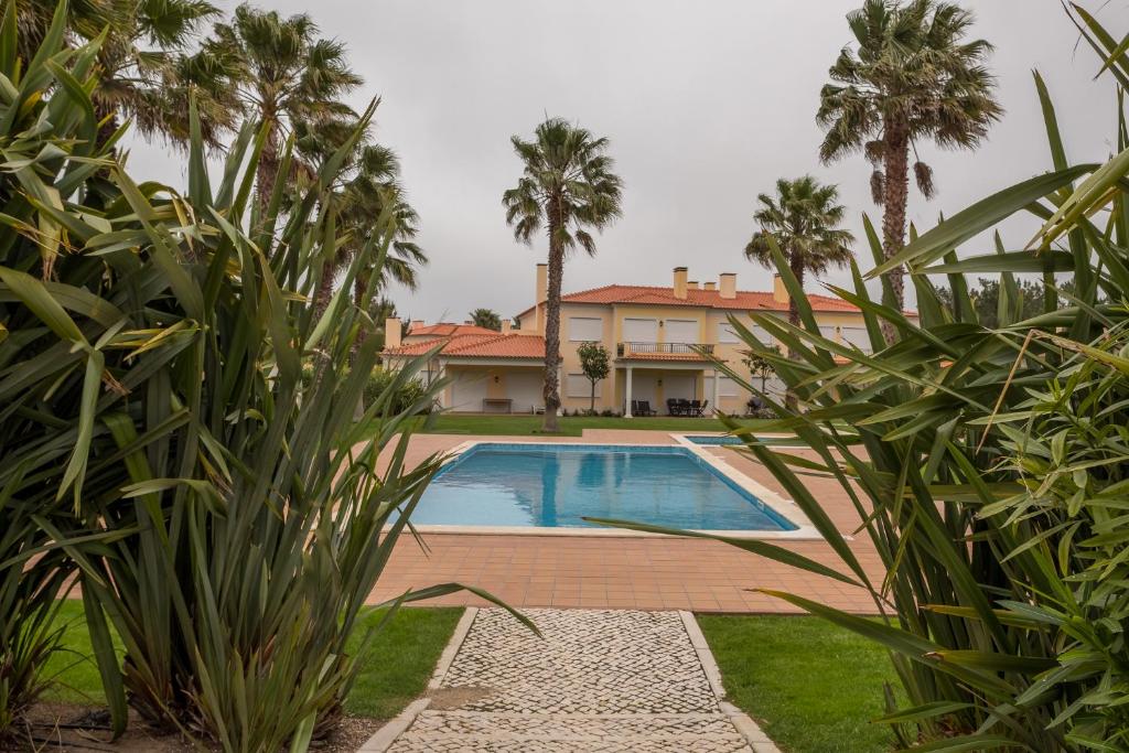 een villa met een zwembad en palmbomen bij T3 Sebastião in Casal da Lagoa Seca