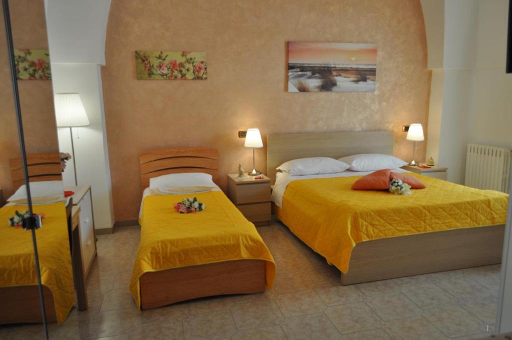 two beds in a hotel room with yellow sheets at 7 Contrade in Taranto