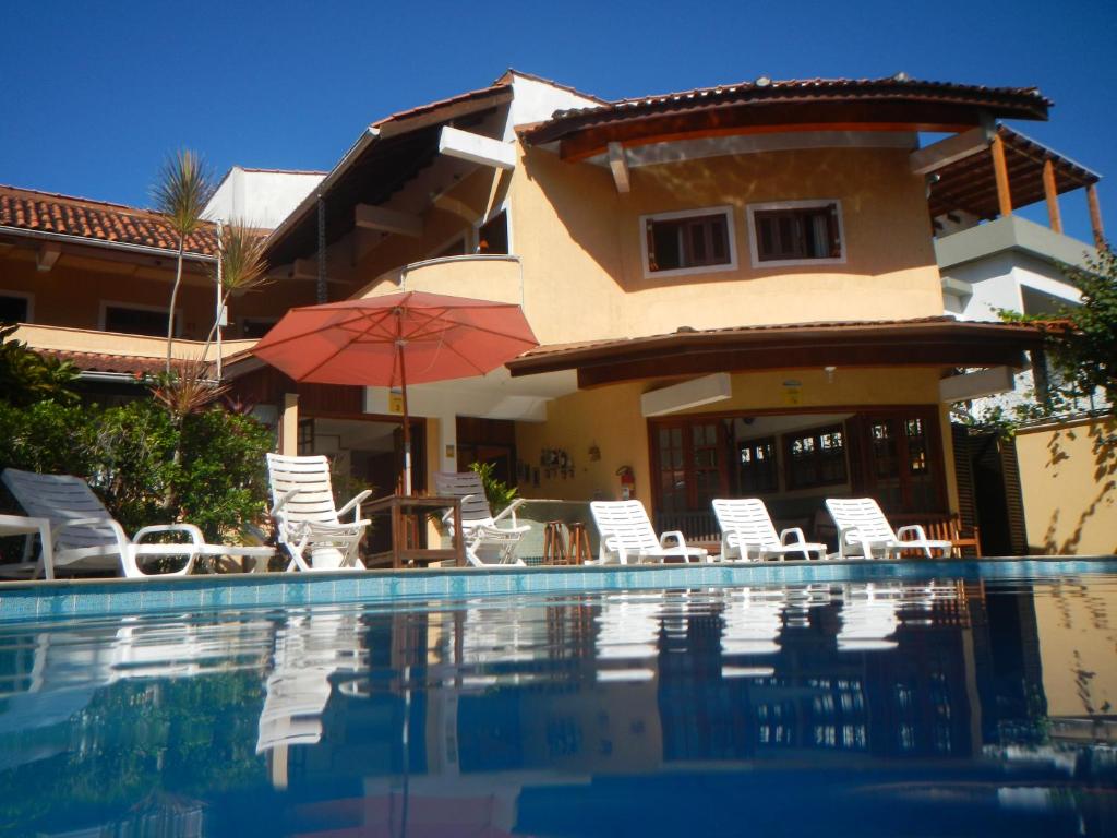 Casa con piscina con sillas y sombrilla en Pousada Mosaico Brasil - Maresias en Maresias