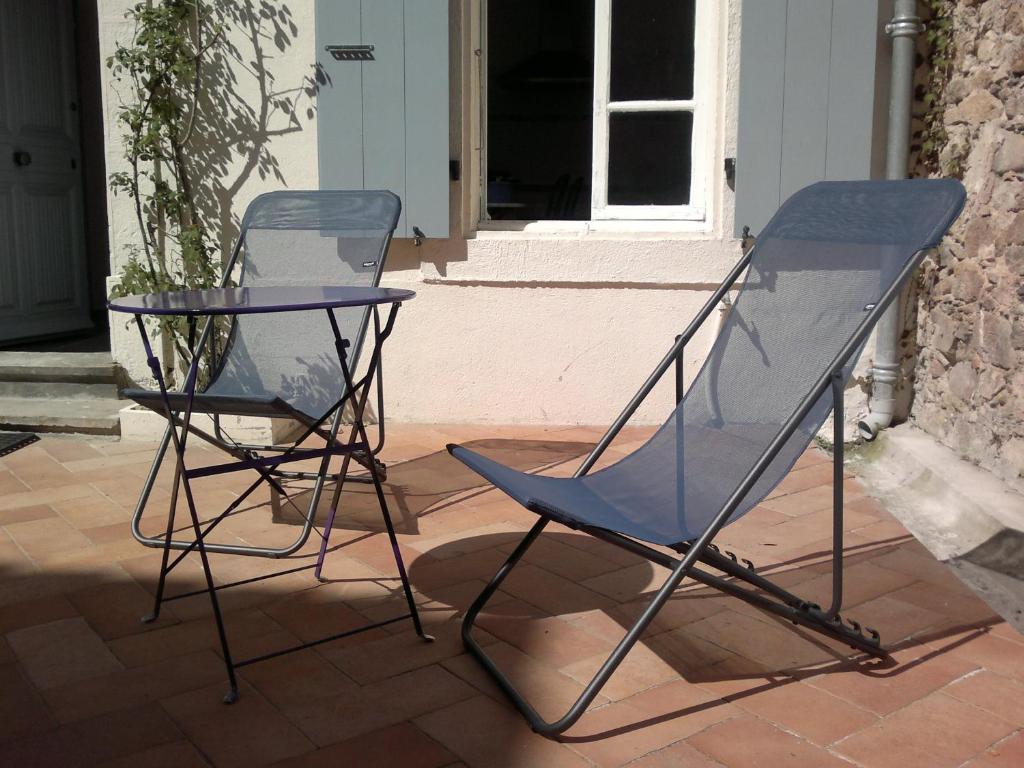 two chairs and a glass table on a patio at Chez Clémentine in Montolieu